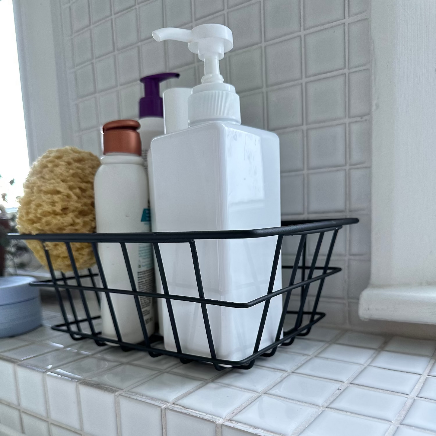 Black wire caddy with bottles on a tiled bathroom counter