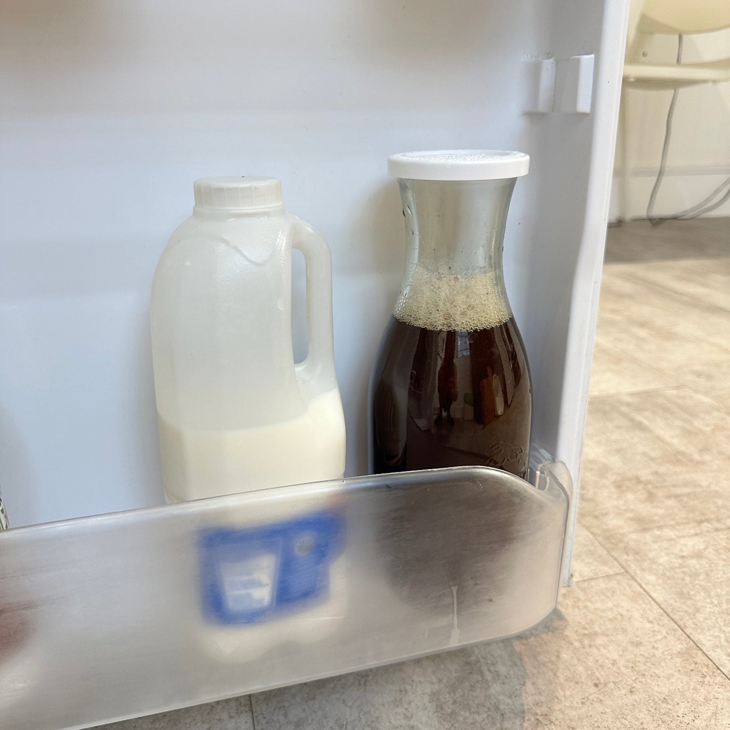 Inside of fridge with bottle of milk and a Weck Carafe with ice tea