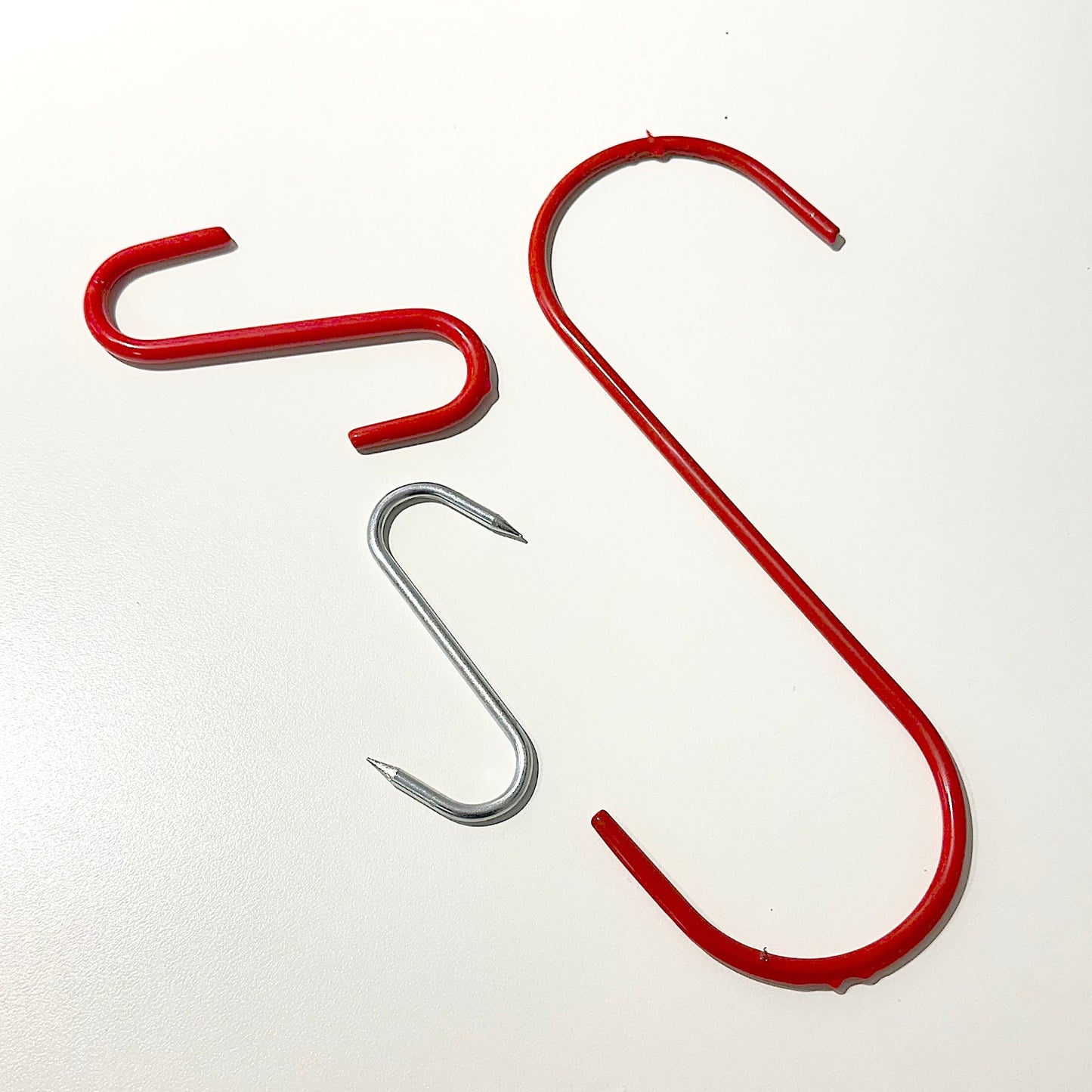 Three red and steel s hooks on white background