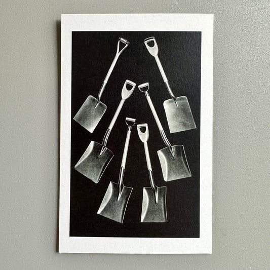 Black and white image of small shovels arranged on a dark background