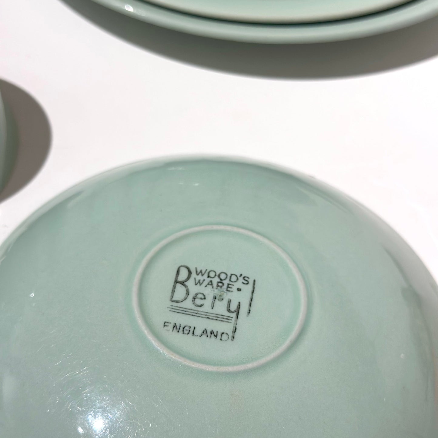 Stack of light green ceramic bowls with 'Wood's Ware' branding on a white background
