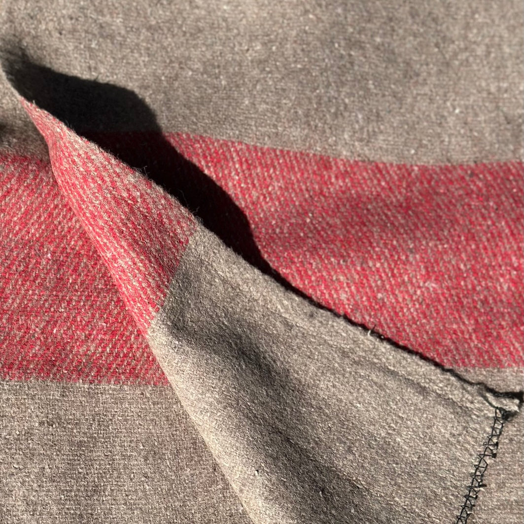 Close-up of a light brown and red blanket with a broad red stripe