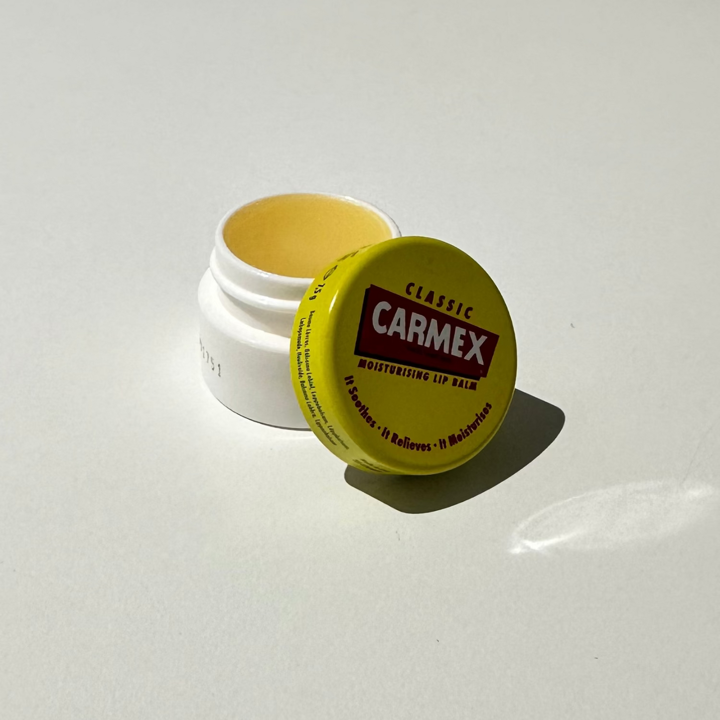 Carmex lip balm container on a white surface