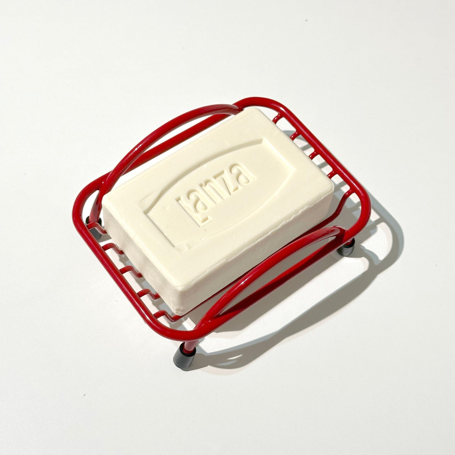 Bar of soap on a red soap dish with branding on a white background