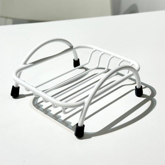 White coated metal soap holder on a white surface with a neutral background