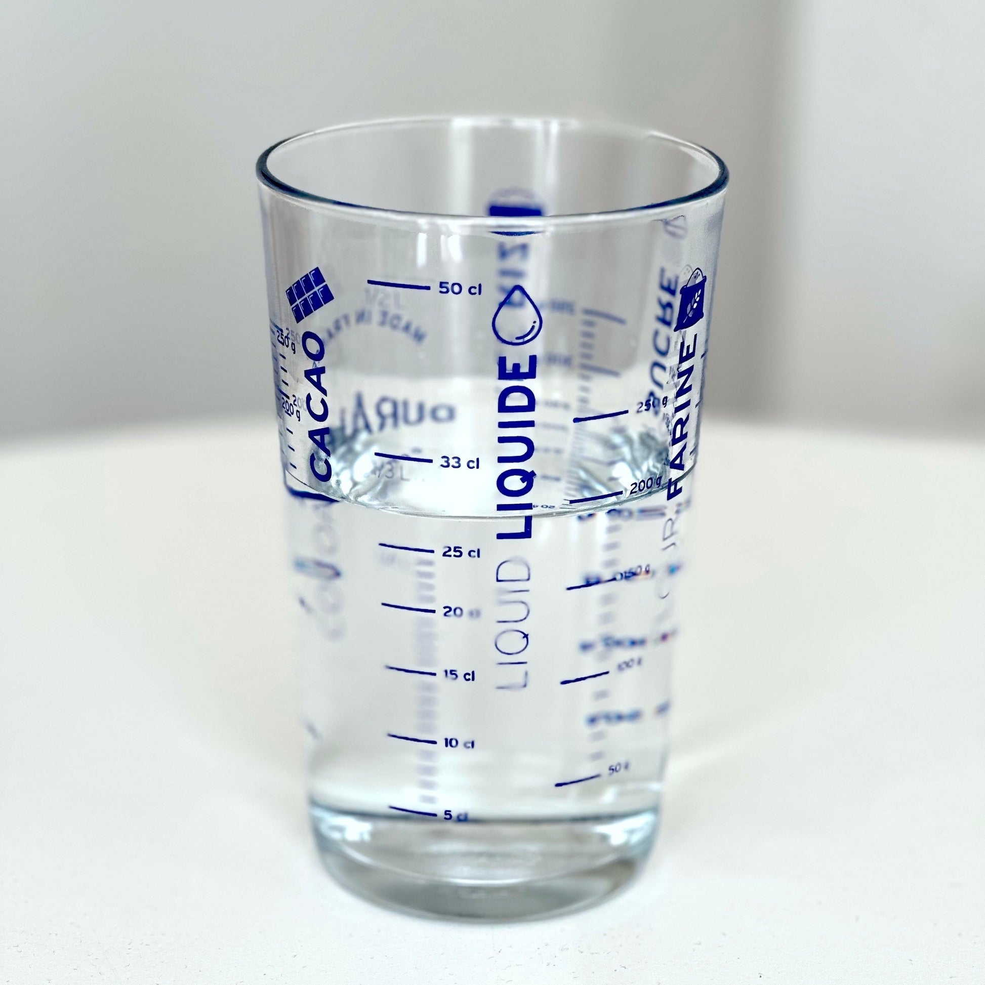 Duralex measuring glass with water white background