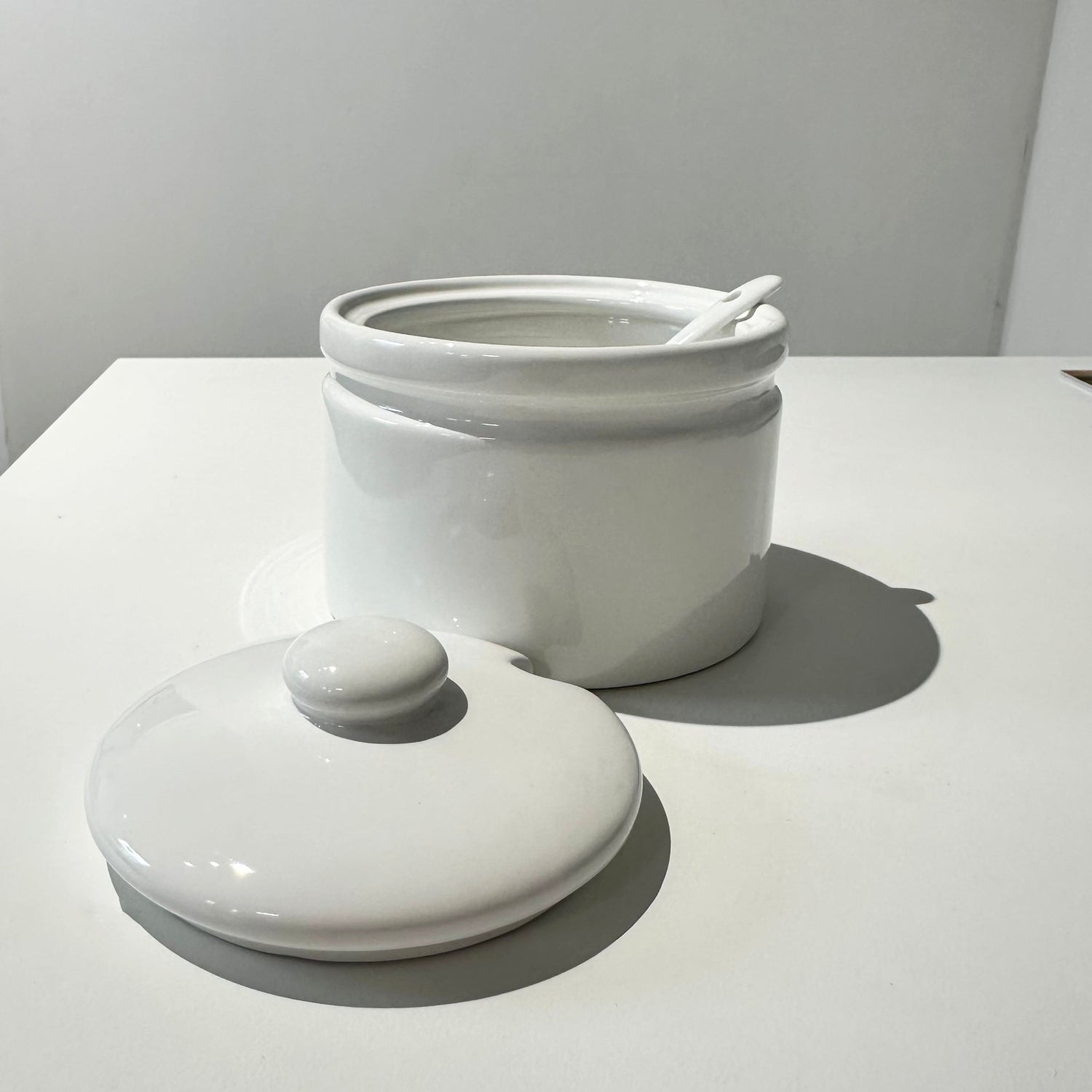 White ceramic jar with a lid on a light gray surface