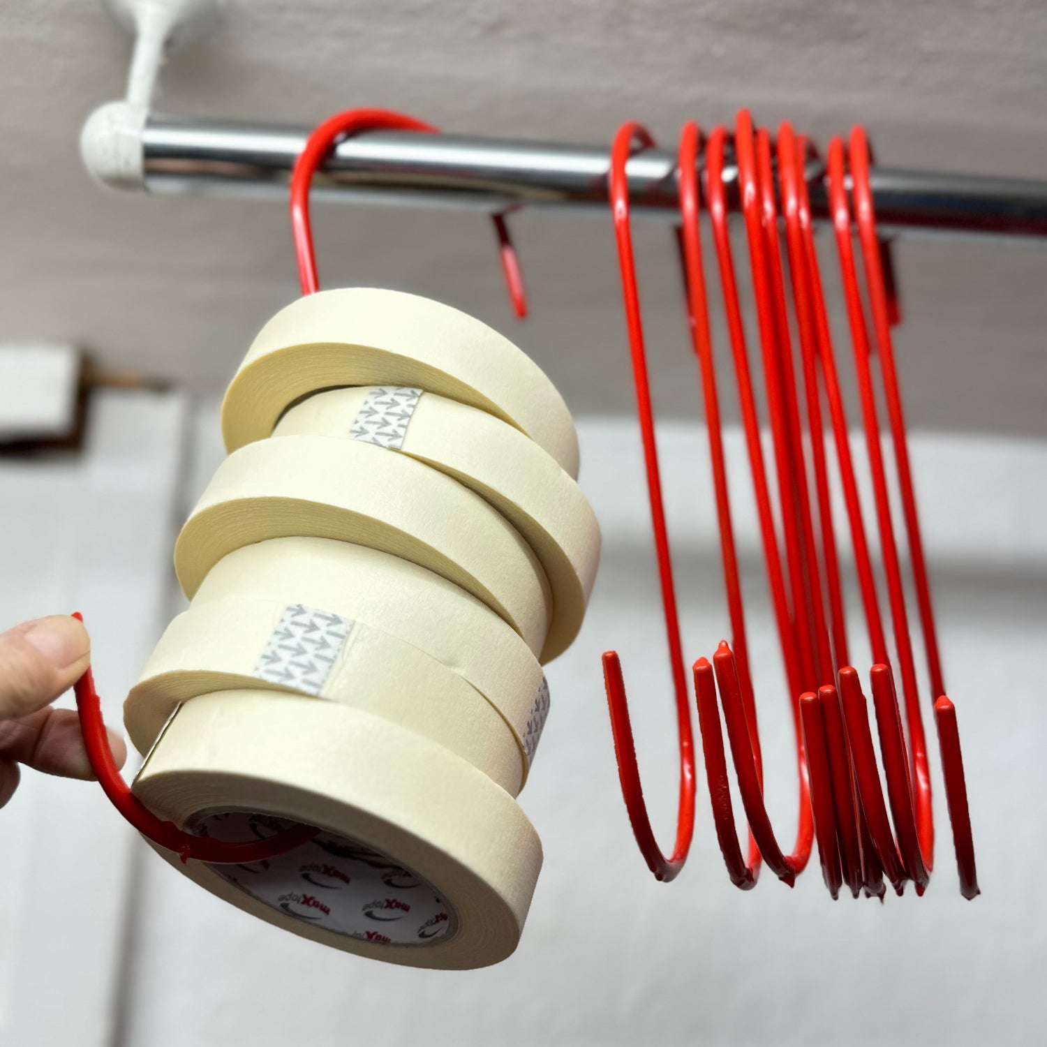 Large red S hooks on rail with rolls of tape