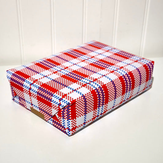 Present wrapped with red, white, and blue plaid pattern gift wrap on a white surface.