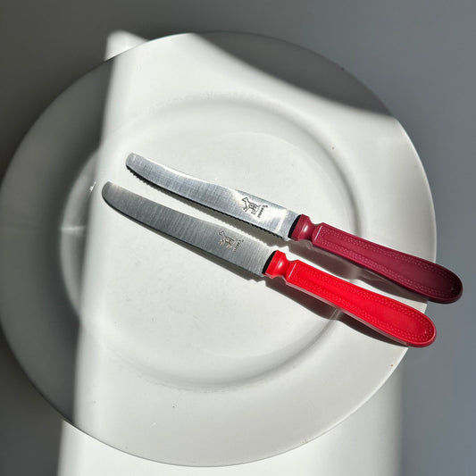 Two "Le Chien" knives on a white plate with a grey background