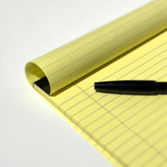 Legal pad detail with black pen and page turned