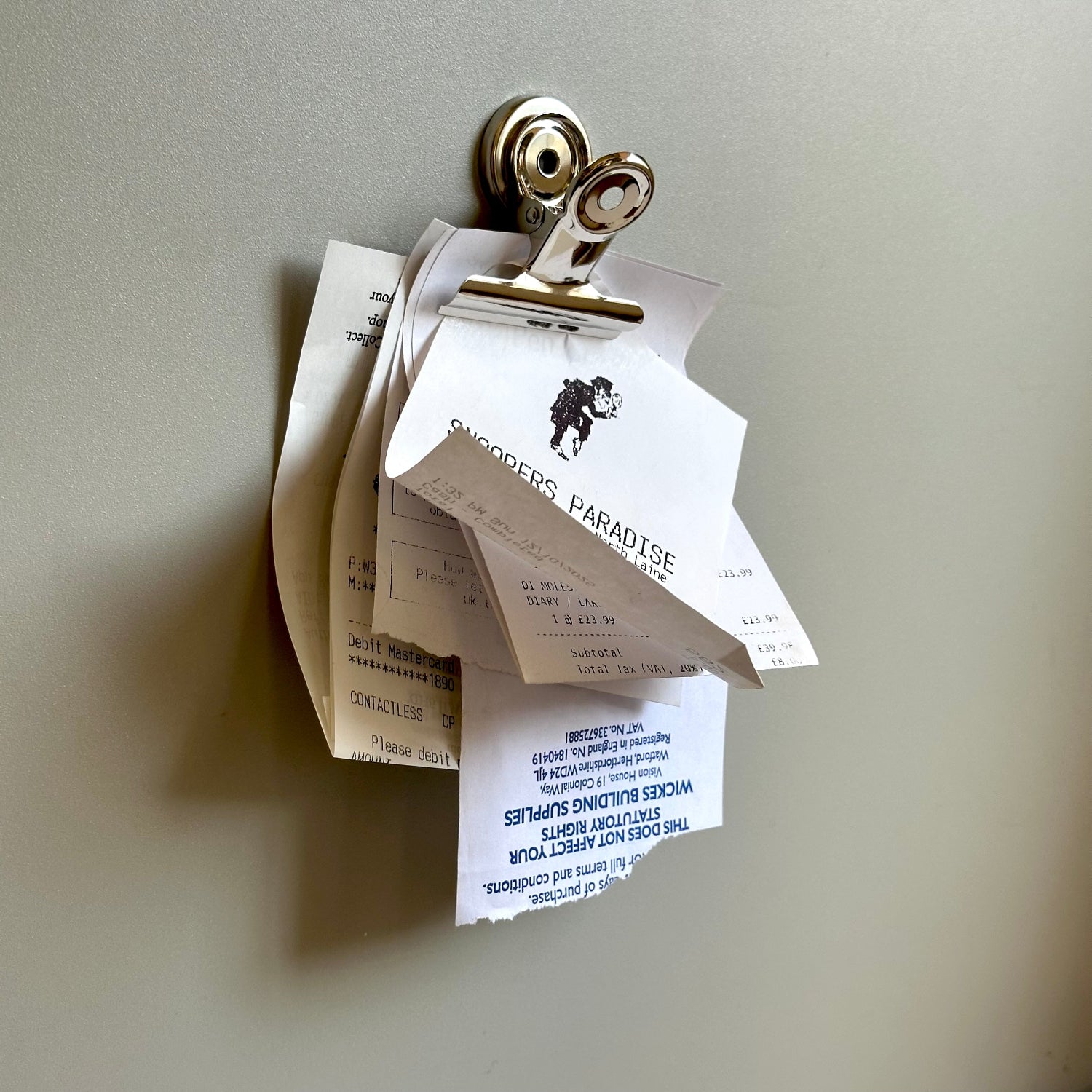Clipboard with receipts and a business card on a plain background