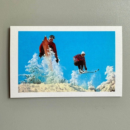Framed picture of two skiers in a snowy landscape with a blue sky.