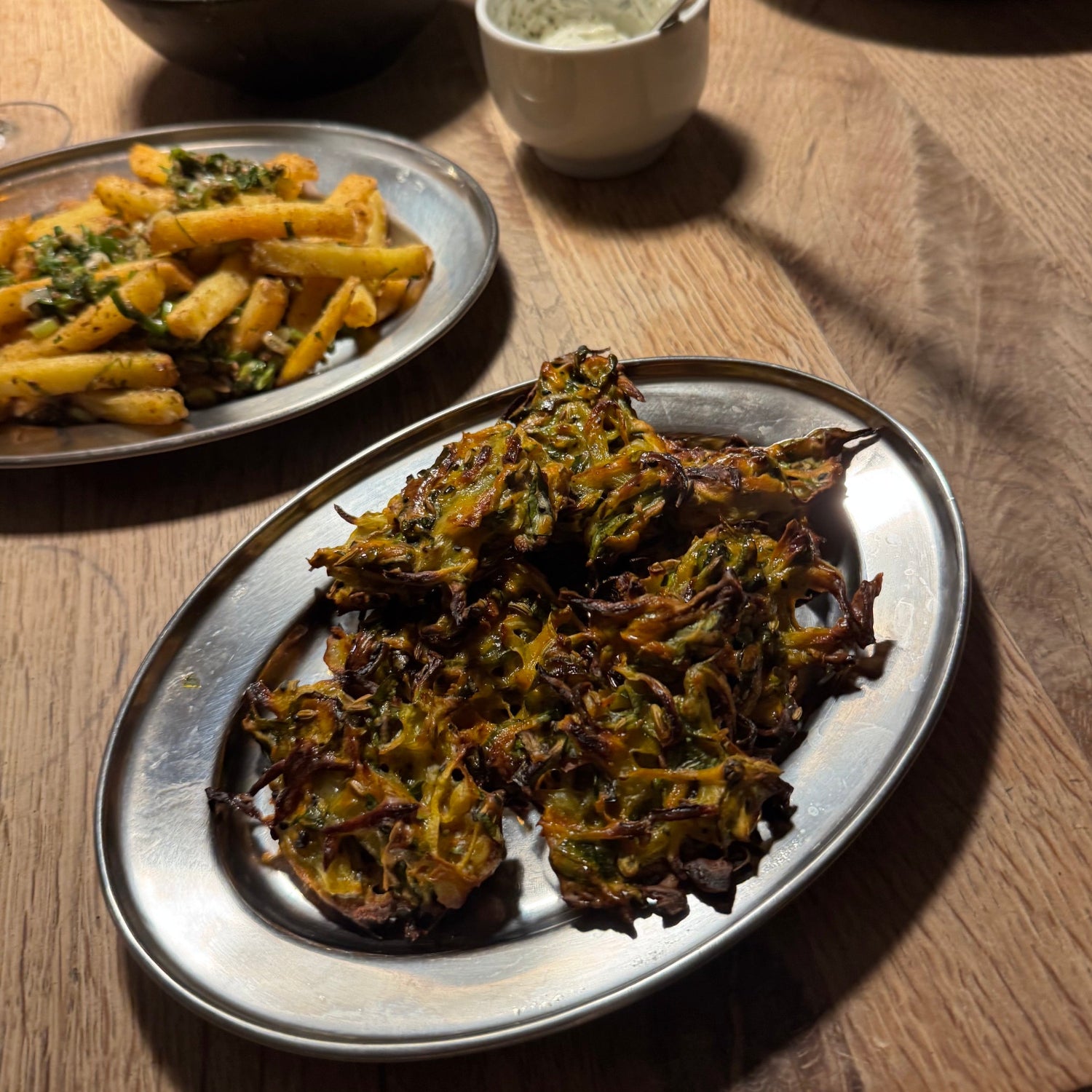 Oval stainless meat flats with food on wooden table