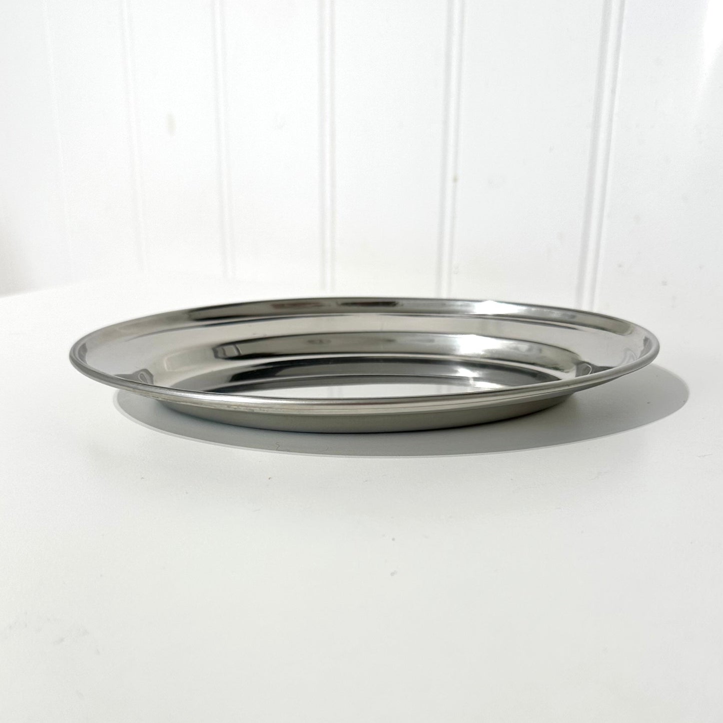 Silver metal tray on a white surface with a white background