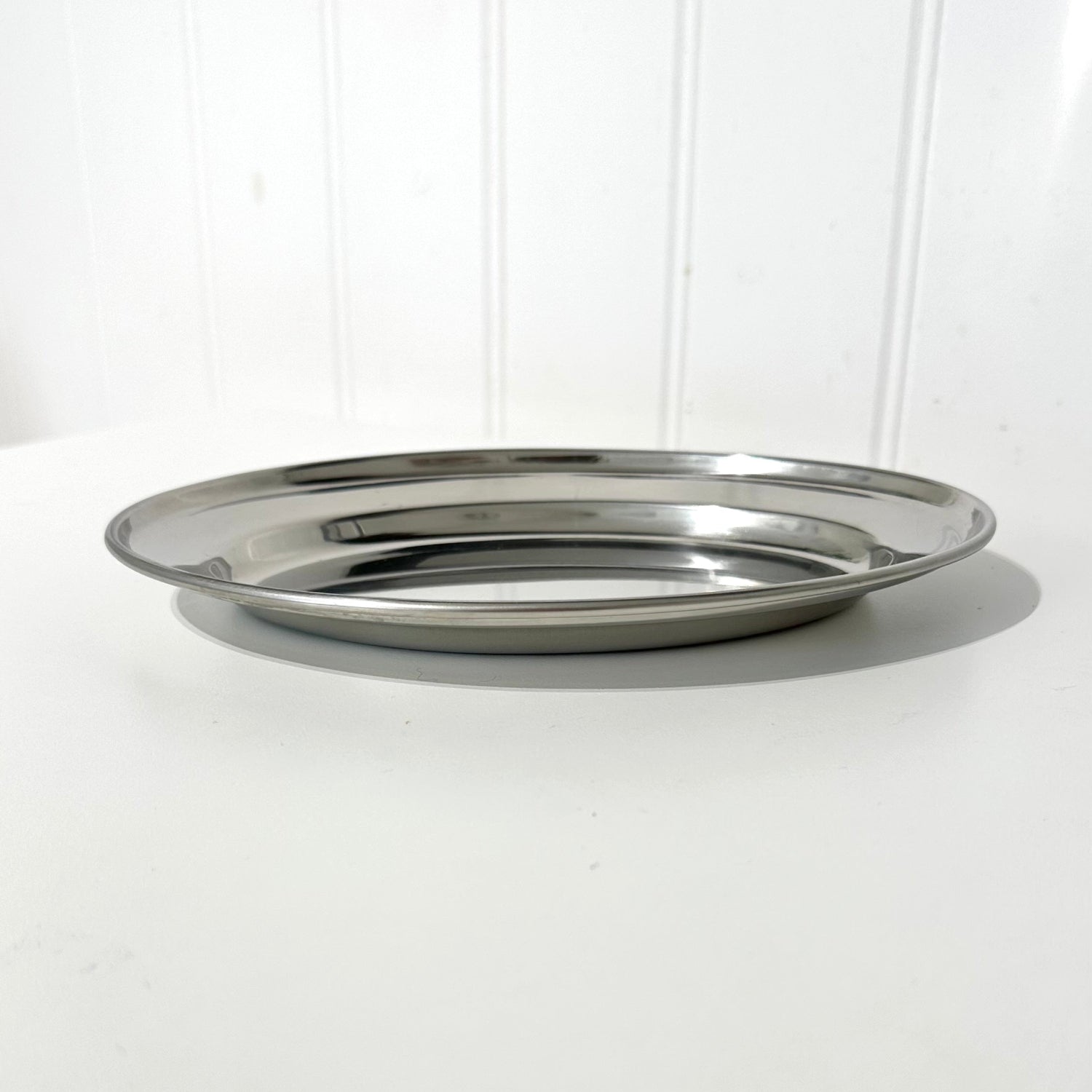 Silver metal tray on a white surface with a white background