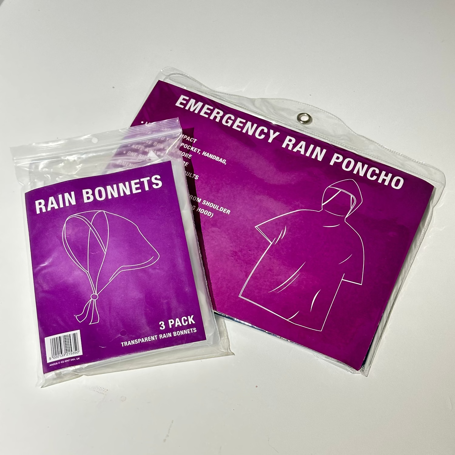 Two packages of rain accessories on a white surface, one labeled 'Rain Bonnets' and the other 'Emergency Rain Poncho'.