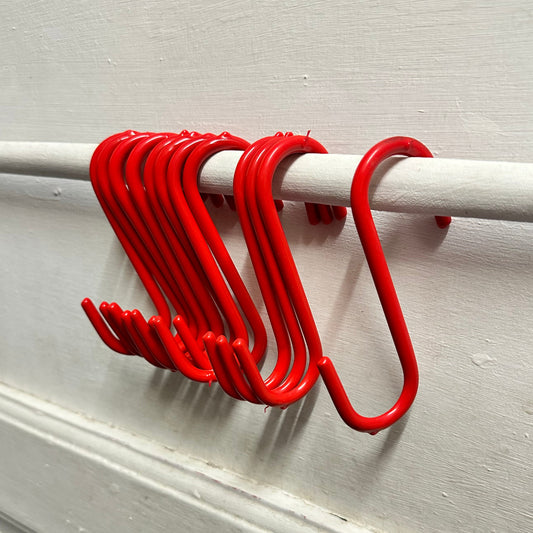 Red S hooks in a row on a rail