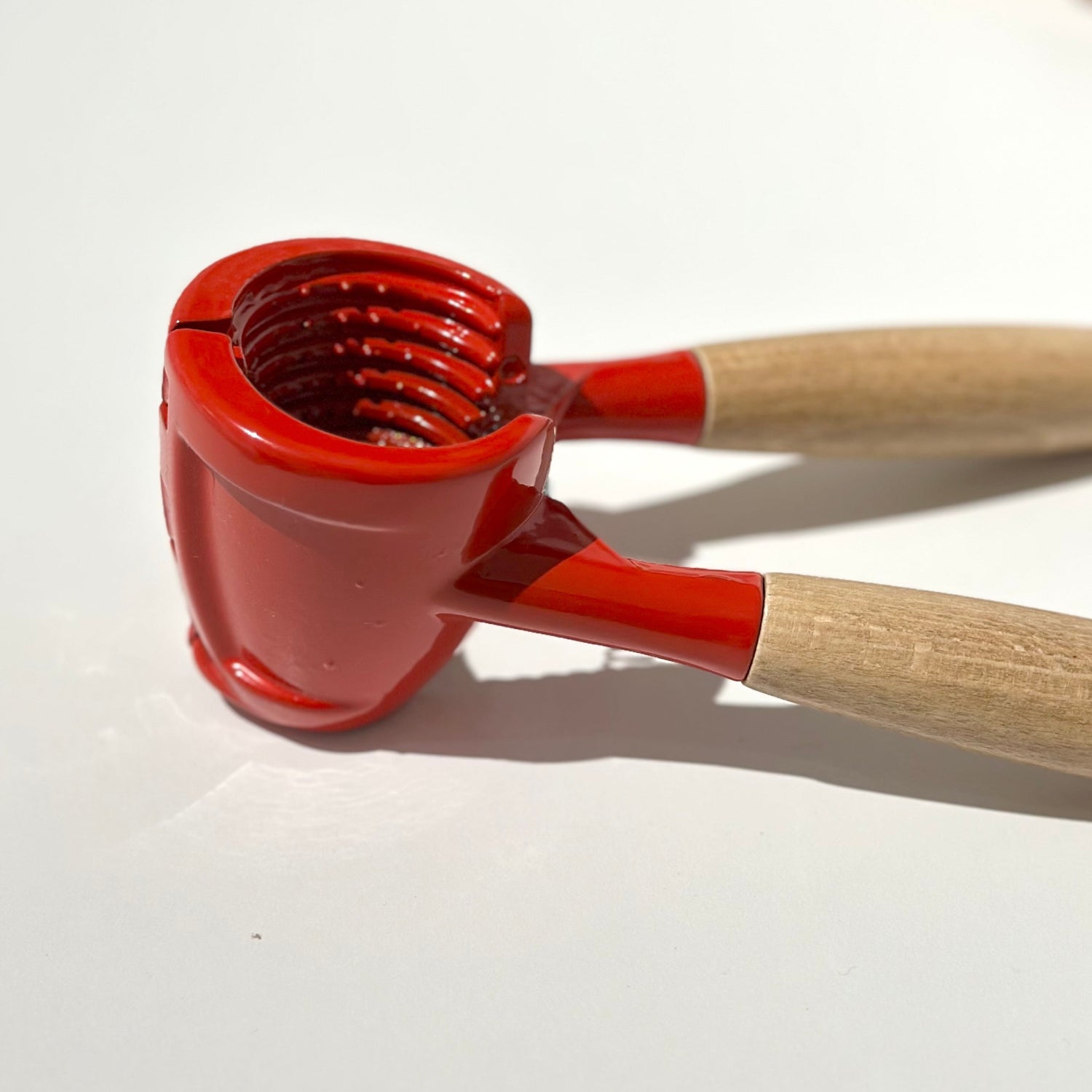 Red nutcracker with wooden handles on a white surface