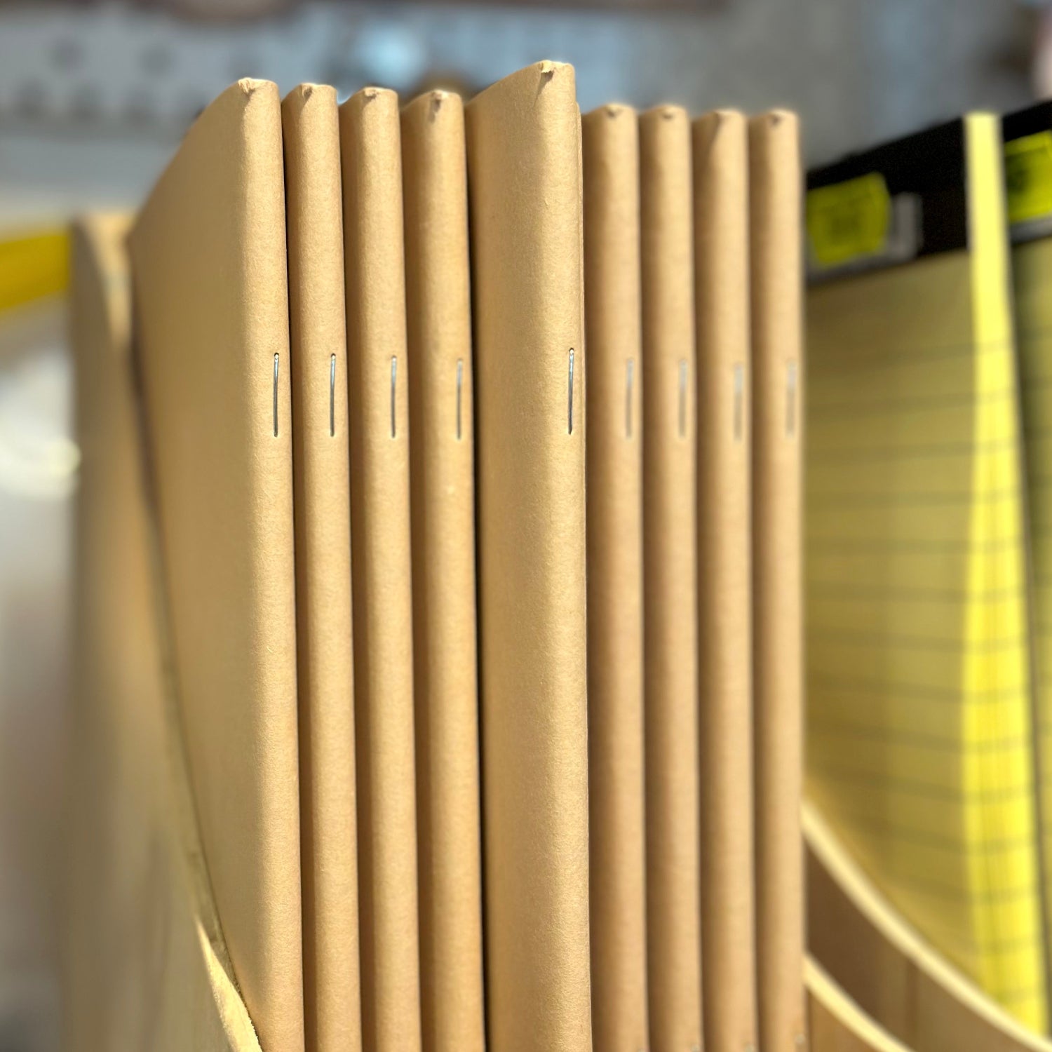 Row of buff coloured sketch books in a wooden holder with a blurred background