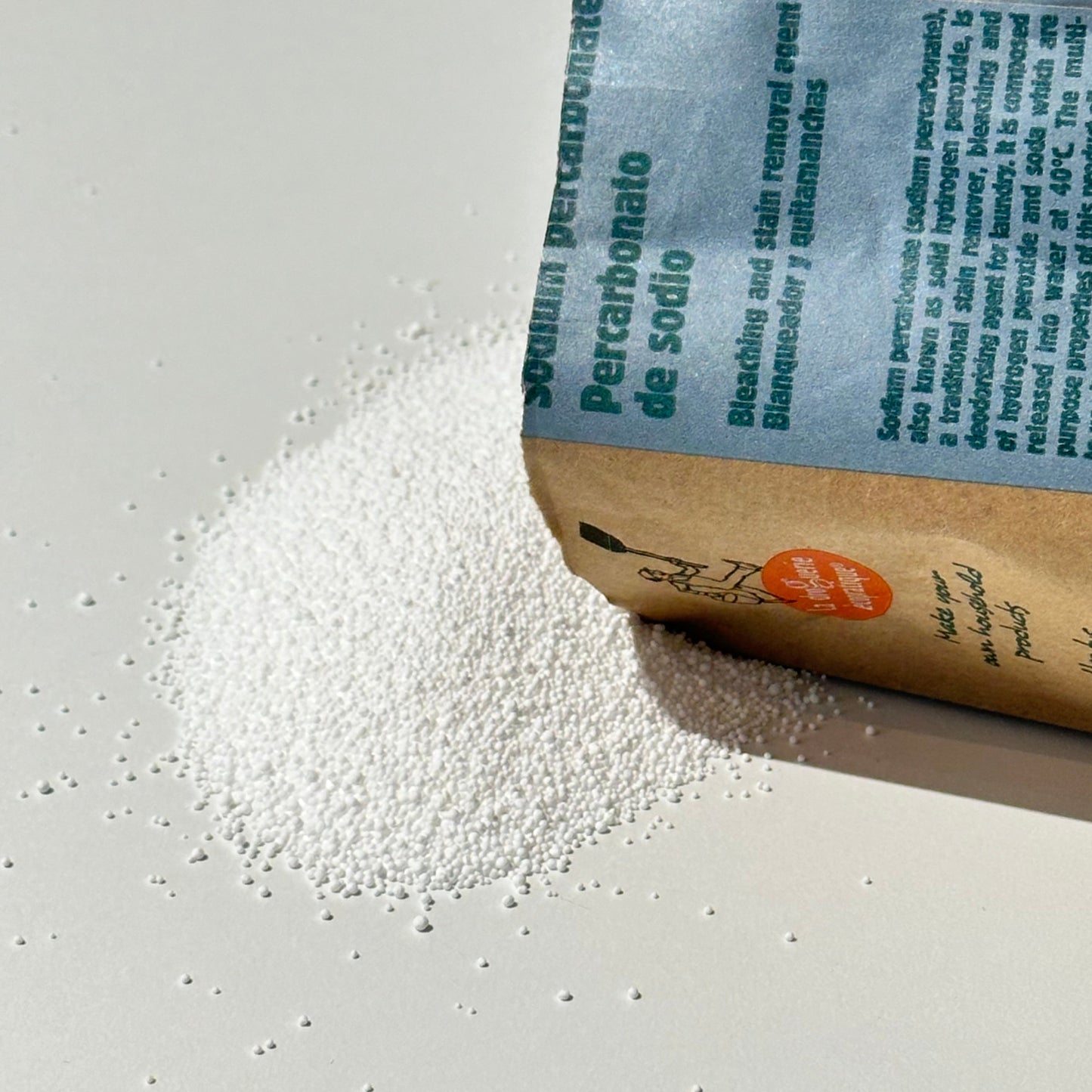Paper bag of sodium percarbonate pouring granules on a white background