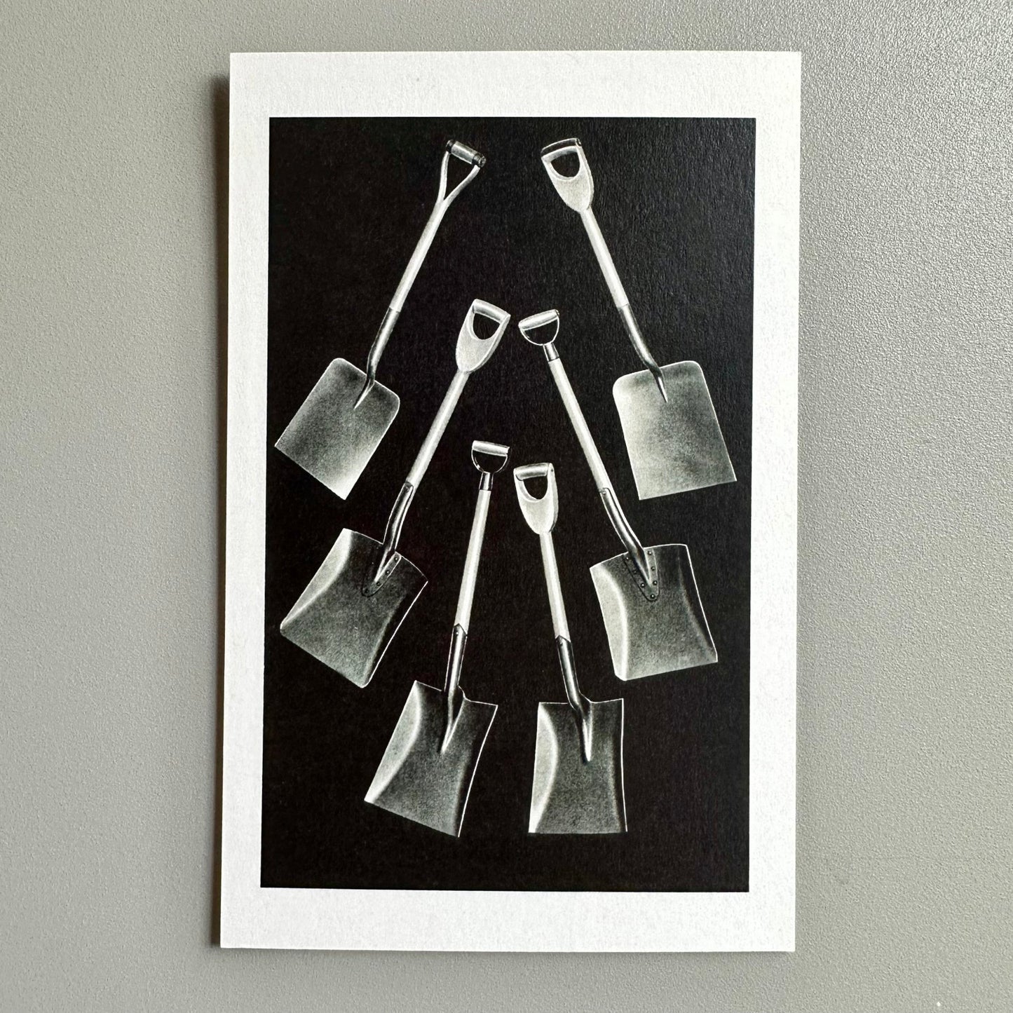 Black and white image of small shovels arranged on a dark background