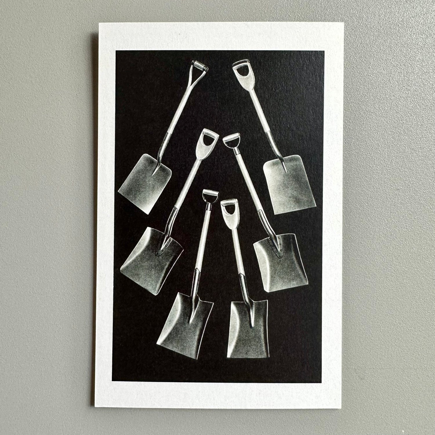 Black and white image of small shovels arranged on a dark background