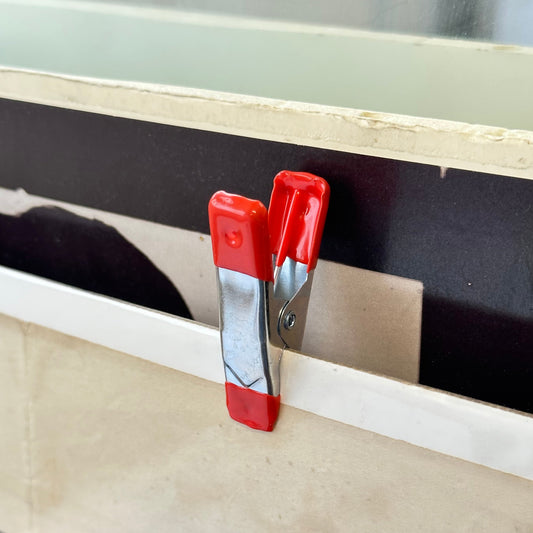 Red and silver clip on a wooden surface with a blurred background