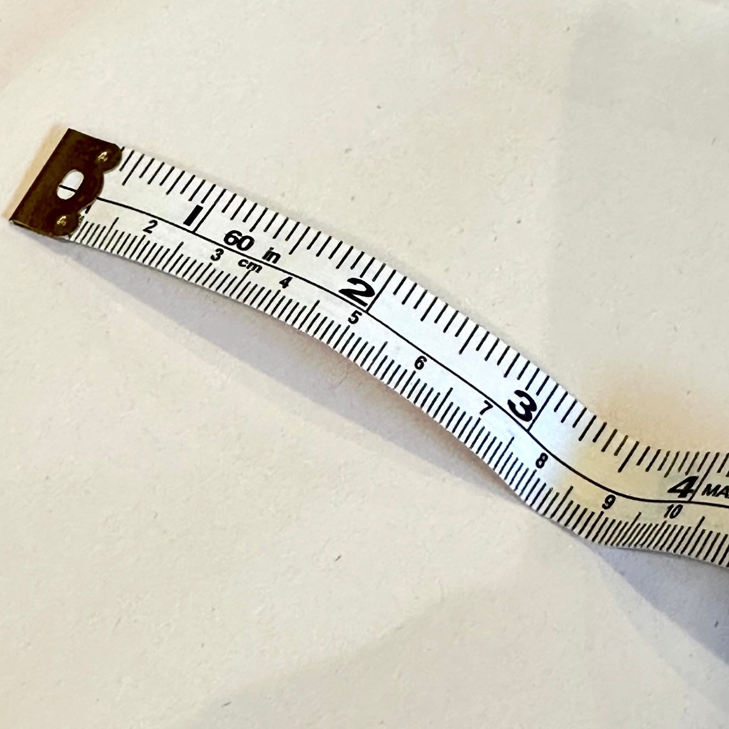 Measuring tape on a white surface with plastic wrap in the background