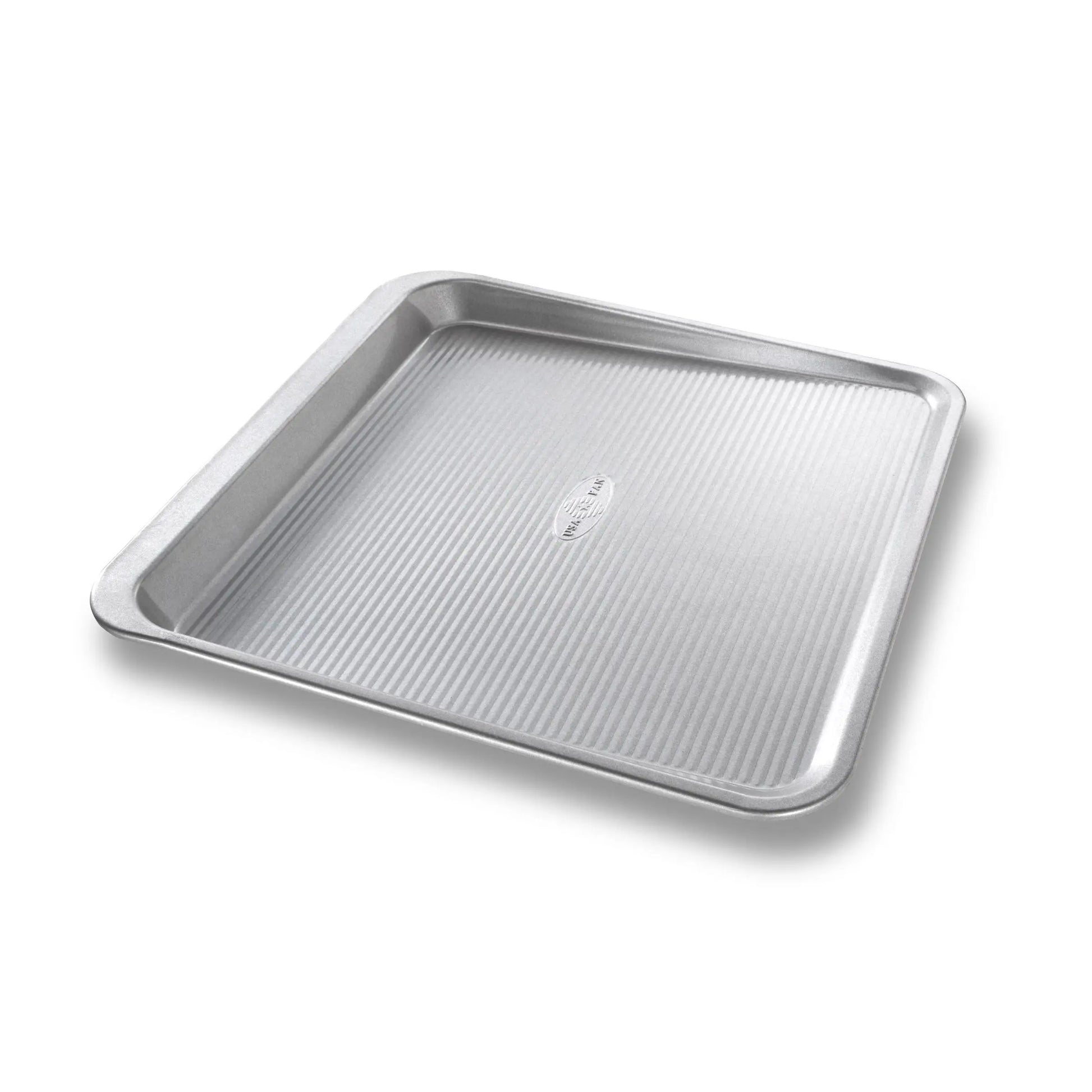 A square stainless steel baking pan with a ribbed textured bottom and raised rim, shown at an angle on a white background.