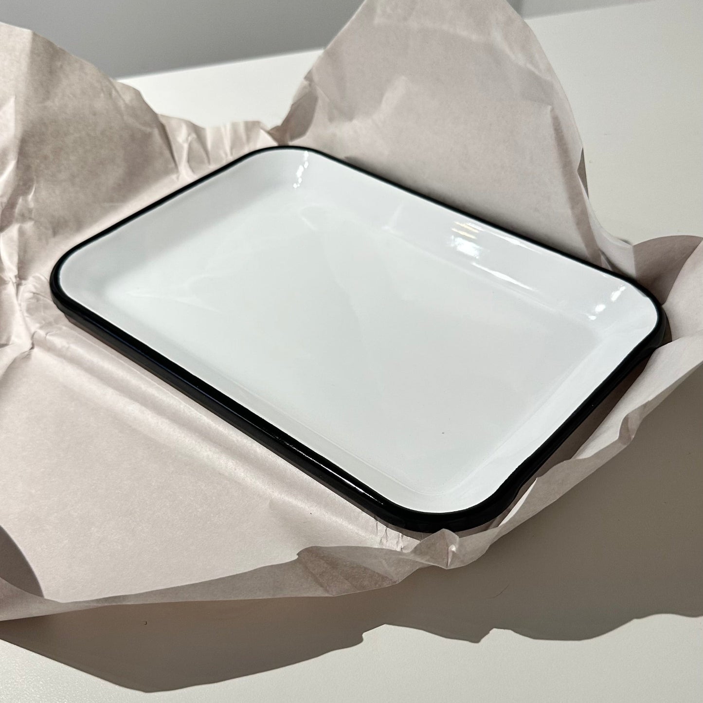 small enamel tray, white with black rim on paper
