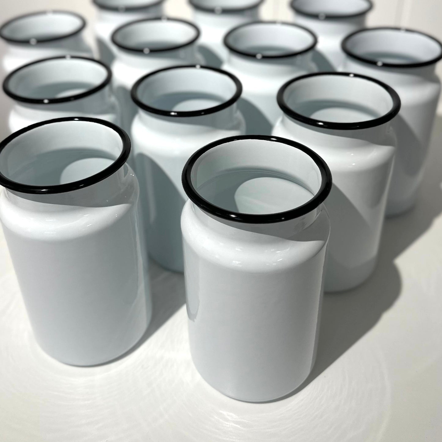 Group of Utility brand white enamel toilet brush holders with black rims on a white surface.