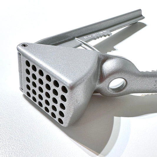 Metal garlic press on a white surface