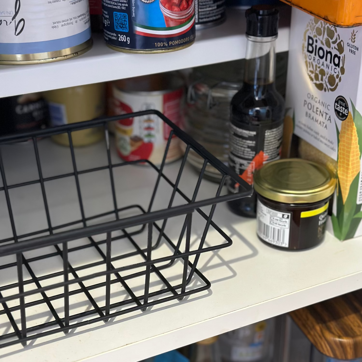 Shelving unit with various food items with black wire storage basket