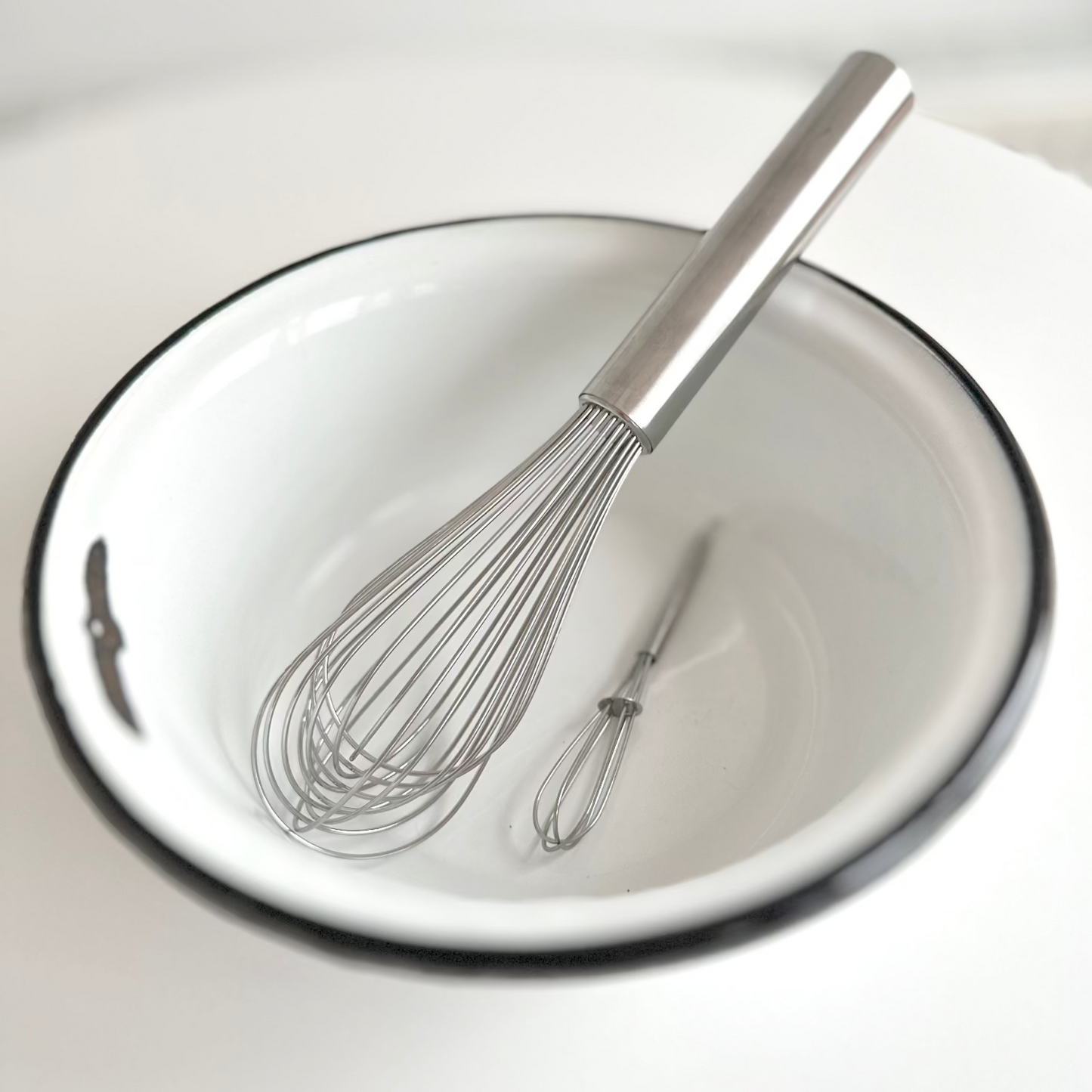White bowl with a whisk inside on a white background