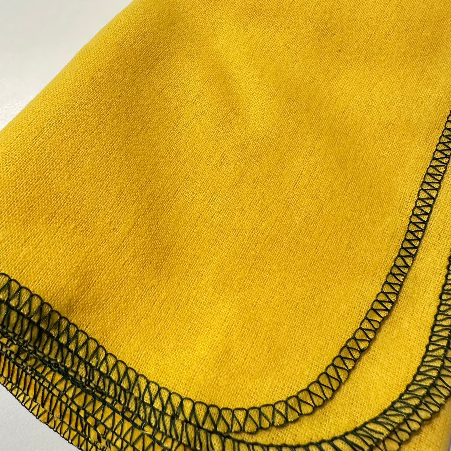A close-up of a yellow duster with a stitched edge.